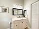 Neutral bathroom with a black framed mirror, marble countertop and bright overhead lighting at 10360 Crystal Point Dr, Orlando, FL 32825