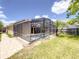 A view of the back exterior of the home shows a screened-in pool, grass yard, and patio at 10360 Crystal Point Dr, Orlando, FL 32825