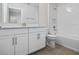 Well-lit bathroom features a white vanity with double sinks, a tiled shower-tub combo, and wood-look tile flooring at 11027 Hollow Bay Dr, Winter Garden, FL 34787