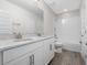 Well-lit bathroom features a white vanity with double sinks, a tiled shower-tub combo, and wood-look tile flooring at 11027 Hollow Bay Dr, Winter Garden, FL 34787
