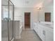 Modern bathroom with double vanity, tiled floors, glass shower, and a view to the walk-in closet at 11027 Hollow Bay Dr, Winter Garden, FL 34787