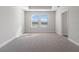 Bright bedroom featuring plush carpeting, a tray ceiling, and a view of the neighborhood from two sunny windows at 11027 Hollow Bay Dr, Winter Garden, FL 34787