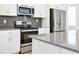 Kitchen with stainless steel appliances, white cabinetry, and stone countertops with modern tile backsplash at 11288 Listening Dr, Orlando, FL 32832