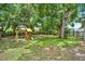 Large backyard with a playset and plenty of space for outdoor activities under mature trees at 1210 Quintuplet Dr, Casselberry, FL 32707