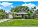 Charming one-story home with lush green lawn, mature landscaping, and a white garage door at 1210 Quintuplet Dr, Casselberry, FL 32707