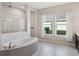Bright bathroom featuring a tiled walk-in shower, soaking tub, and dual windows providing natural light at 1265 Estancia Woods Loop, Windermere, FL 34786