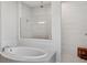 Bright bathroom features a tub and separate glass-enclosed shower with sleek white tiling at 1265 Estancia Woods Loop, Windermere, FL 34786