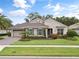 Charming single-Gathering home showcasing stone accents, a manicured lawn, colorful flowerbeds, and a paved driveway at 1265 Estancia Woods Loop, Windermere, FL 34786