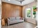 Relaxing living room featuring a gray couch, wood-paneled accent wall, and bright natural light at 1265 Estancia Woods Loop, Windermere, FL 34786
