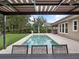Backyard pool with travertine deck, covered seating, and lush landscaping creating a private oasis at 1265 Estancia Woods Loop, Windermere, FL 34786