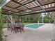 Beautiful backyard pool with covered dining area, lush landscaping, and travertine tile at 1265 Estancia Woods Loop, Windermere, FL 34786