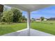 Covered patio view featuring green grass and a house with a red roof in the distance at 14470 Sw 46Th Ct, Ocala, FL 34473