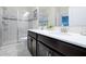 Bathroom features double sinks with white countertops, dark cabinets, and a glass door shower at 1521 Flange Dr, Davenport, FL 33896
