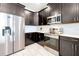 Bright kitchen featuring stainless steel appliances, dark cabinets, and light blue backsplash with modern white floors at 1521 Flange Dr, Davenport, FL 33896