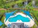 Aerial view of the community pool area, featuring a clear blue swimming pool, shaded lounge area and a picturesque pond at 15822 Woodland Spring Ct, Orlando, FL 32828