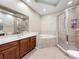 Bathroom featuring dual sinks, a bathtub, and a separate shower stall with modern fixtures and finishes at 15822 Woodland Spring Ct, Orlando, FL 32828