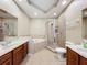 Bathroom featuring dual sinks, a bathtub with tile surround, and a glass-enclosed shower, creating a spa-like atmosphere at 15822 Woodland Spring Ct, Orlando, FL 32828