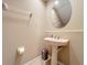 Compact powder room featuring a pedestal sink, round mirror, and neutral color scheme at 15822 Woodland Spring Ct, Orlando, FL 32828