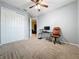 Bright bedroom featuring a ceiling fan, beige carpet, and a functional workspace with desk and rolling chair at 15822 Woodland Spring Ct, Orlando, FL 32828