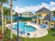 Community pool surrounded by manicured grounds and featuring ample seating and shaded area at 15822 Woodland Spring Ct, Orlando, FL 32828