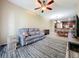 Cozy living room featuring a gray sofa, ceiling fan, and open layout leading to the dining area at 15822 Woodland Spring Ct, Orlando, FL 32828