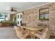 Cozy covered patio with brick walls, a ceiling fan, and wicker seating around a glass-top table at 1778 Woodcrest Ln, Deland, FL 32720