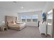 Bright bedroom featuring plush carpet, large windows, and a tufted headboard at 1932 Terrapin Rd, Ocoee, FL 34761