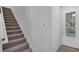 Interior view of a staircase and front door, featuring neutral walls and carpeted steps at 1932 Terrapin Rd, Ocoee, FL 34761