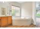 Bright bathroom featuring a soaking tub and vanity with cabinet storage with backyard views at 1932 Westpointe Cir, Orlando, FL 32835