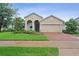 Charming beige home with a brick driveway, a cozy arched entryway, and lush green landscaping at 2339 Jernigan Loop, Kissimmee, FL 34746