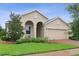 Charming beige home featuring a brick driveway, arched entryway, and well-maintained landscaping at 2339 Jernigan Loop, Kissimmee, FL 34746