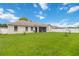 Exterior view of the backyard showing the beige house and green grass at 3250 Sawgrass Creek Cir, St Cloud, FL 34772