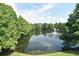 Scenic view of a tranquil lake with a fountain surrounded by lush greenery and mature trees at 335 Lansbrook Ln, Winter Springs, FL 32708