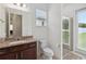 Bathroom featuring granite counters, wooden cabinets, glass shower, and backyard view at 4759 Riverwalk Dr, St Cloud, FL 34771