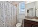 Bathroom with granite vanity top, shower with blue pattern curtain, and a window with a view at 4759 Riverwalk Dr, St Cloud, FL 34771