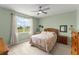 Bright bedroom with a plush bed, ceiling fan, and a sunlit window overlooking the lawn at 5395 Sunshine Dr, Wildwood, FL 34785
