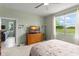 Light-filled bedroom with a ceiling fan, TV, and window views of the outdoor greenery at 5395 Sunshine Dr, Wildwood, FL 34785