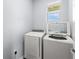 Bright laundry room with new washer and dryer beneath a sunny window at 5395 Sunshine Dr, Wildwood, FL 34785
