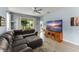 Living room with a large sectional sofa, a TV stand, and sliding glass doors that offer a view of the backyard and natural light at 5395 Sunshine Dr, Wildwood, FL 34785