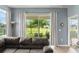 Living room with a comfortable sofa, a large window, and neutral curtains, creating a cozy and inviting space with natural light at 5395 Sunshine Dr, Wildwood, FL 34785