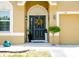 Inviting front door with decorative wreath, lush landscaping, and charming architectural details enhance curb appeal at 608 Washington Way, Haines City, FL 33844