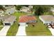 An aerial view shows a gray house with a terracotta colored roof and a screened in pool, surrounded by green lawns at 611 Jura Ln, Kissimmee, FL 34759