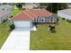 An aerial view showcases a gray home with a new terracotta-colored roof, green lawn and a two car garage at 611 Jura Ln, Kissimmee, FL 34759