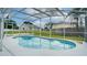 Sparkling in-ground pool surrounded by a screened enclosure and lush landscaping, perfect for relaxation at 611 Jura Ln, Kissimmee, FL 34759