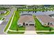 Aerial view of a modern home with a two-car garage, paved driveway, lush lawn and a serene pond at 6348 Mossy Oak Rd, St Cloud, FL 34771