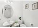 Clean half-bathroom with a pedestal sink, toilet, framed pictures, and decorative plants at 6348 Mossy Oak Rd, St Cloud, FL 34771