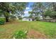 Large backyard featuring a lush lawn, mature trees, and a white house with a sliding glass door leading to a patio at 6505 Dorchester Rd, Lakeland, FL 33809