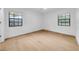 Bright bedroom with neutral paint, light-colored wood floors, and two windows at 6505 Dorchester Rd, Lakeland, FL 33809