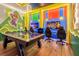 Vibrant game room with air hockey table, gaming chairs, TVs, and cartoon characters on the walls at 10293 Ebb Tide Ln, Orlando, FL 32821