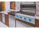 The outdoor kitchen is well-equipped with a built-in grill, marble countertops, and stainless-steel appliances at 10293 Ebb Tide Ln, Orlando, FL 32821